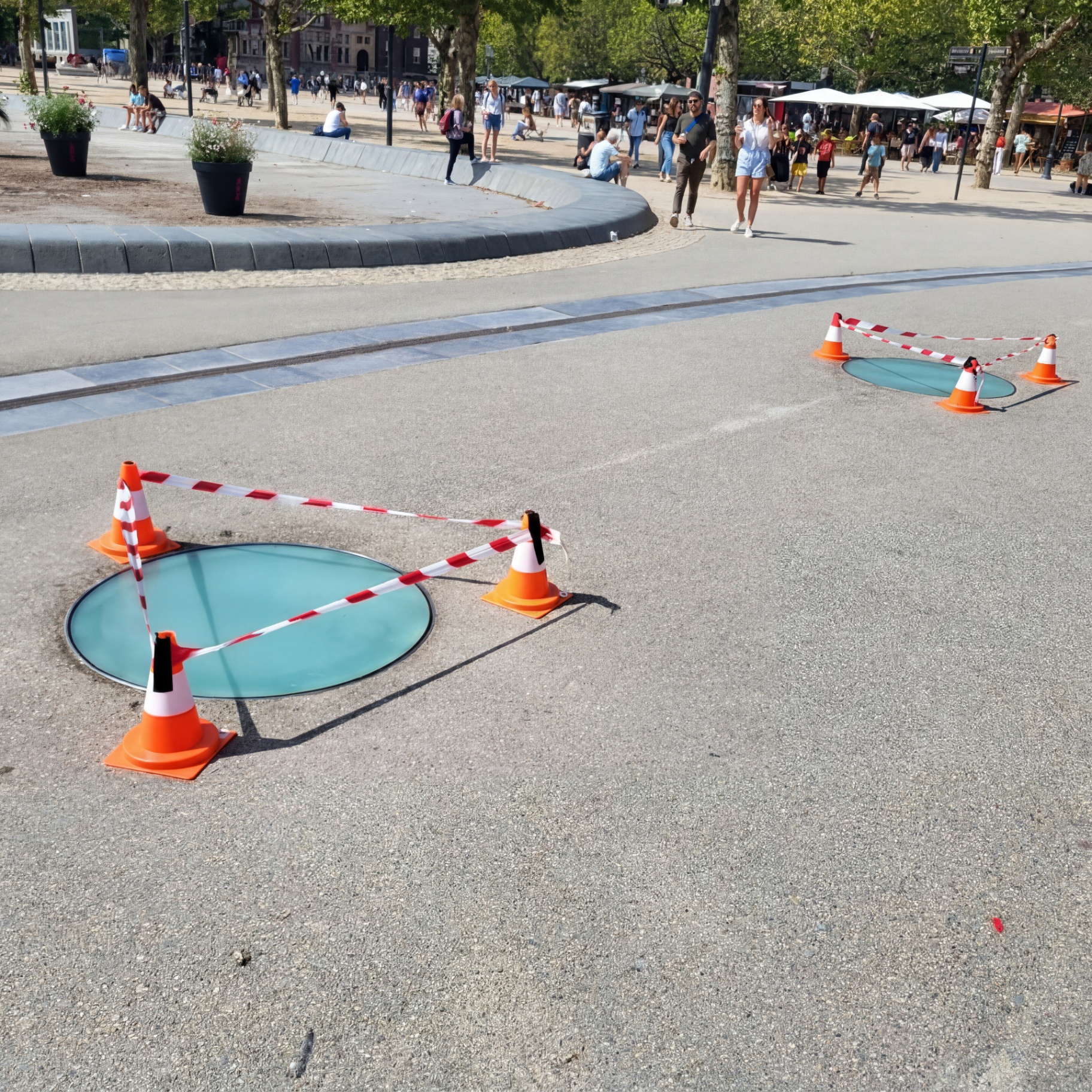 Twee ronde beloopbare glasluiken op het Museumplein in Amsterdam, afgezet met pylonen en lint