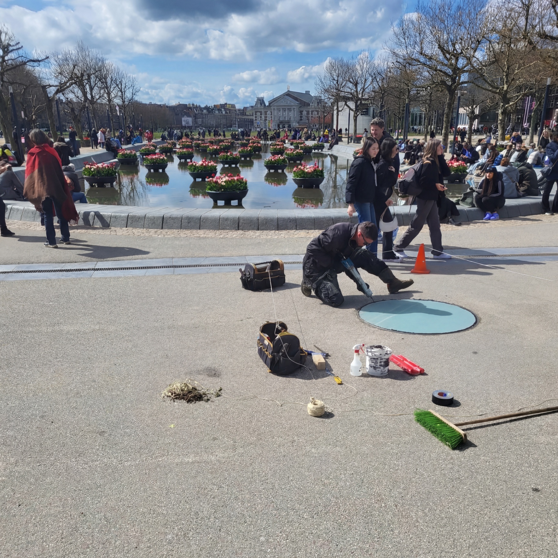 Monteur kit de rand van het ronde beloopbare glas af op het Museumplein, met de tulpenvijver op de achtergrond